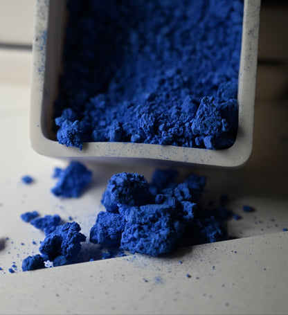 Blue powder spilling out of a container on a light surface
